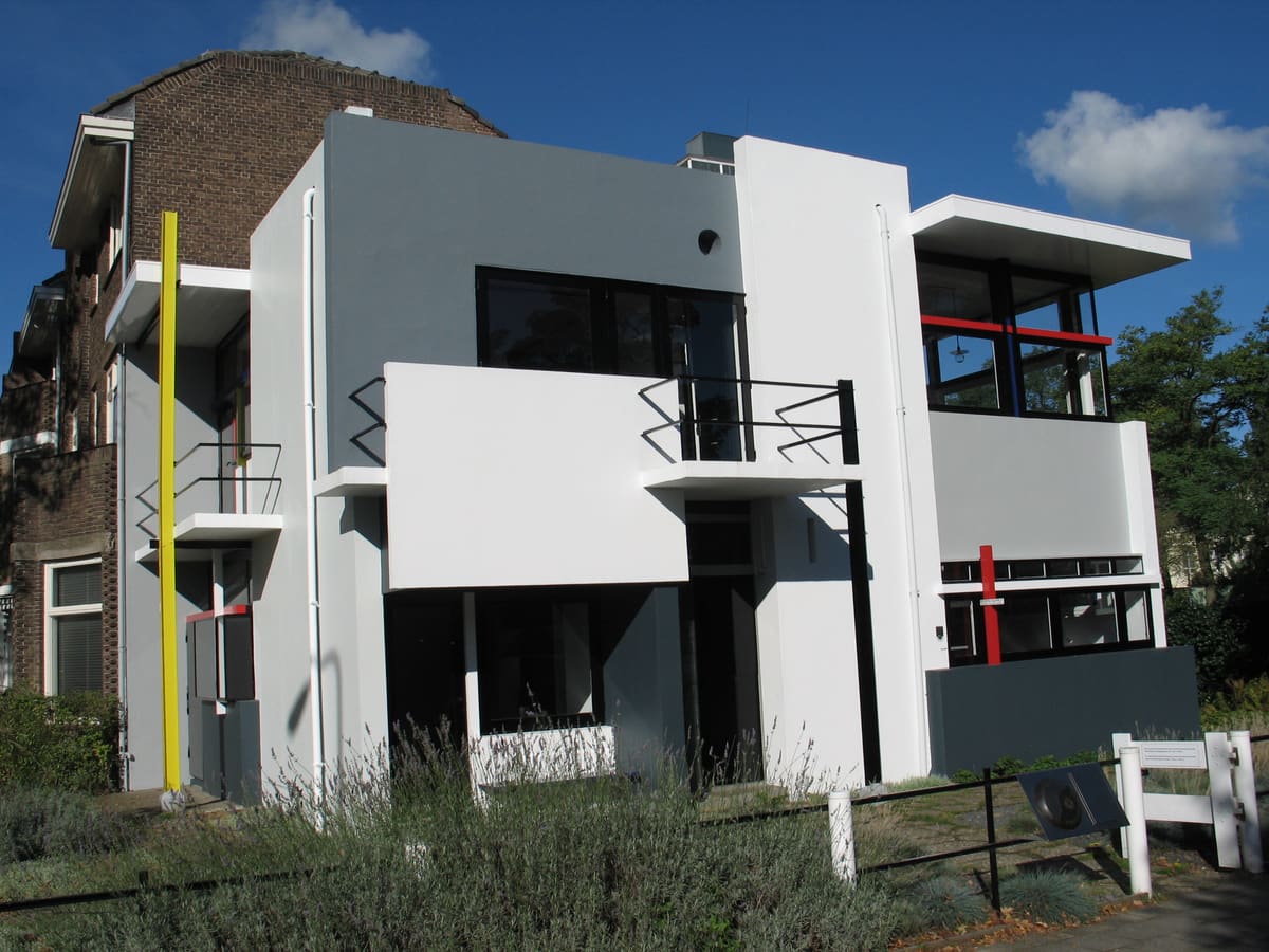 The Rietveld Schröder House in Utrecht: white and grey planes, black window frames, a yellow post and red and blue bars, under a blue sky